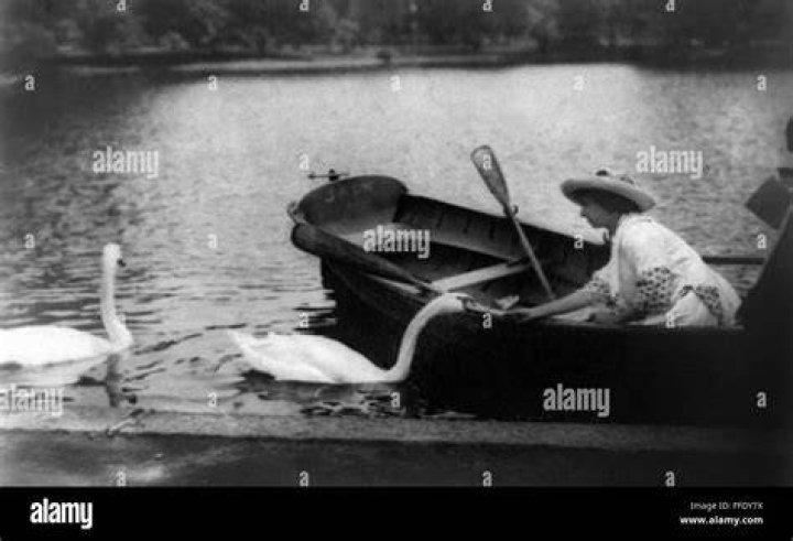 Helen Keller in a rowboat feeding a swan.